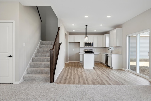 kitchen with appliances with stainless steel finishes, hanging light fixtures, a center island, tasteful backsplash, and white cabinets