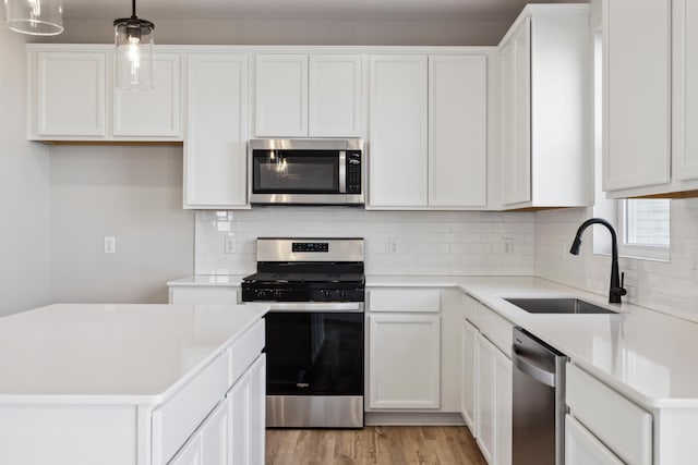 kitchen with appliances with stainless steel finishes, white cabinets, and decorative light fixtures