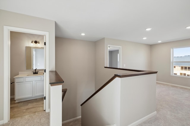 hall featuring sink and light carpet