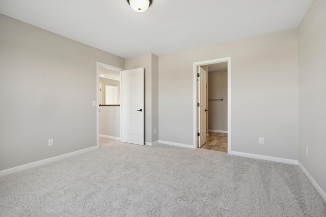 unfurnished bedroom with light carpet and a spacious closet