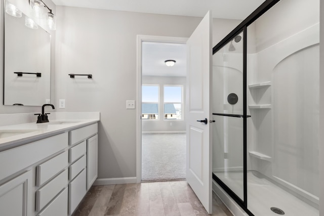 bathroom featuring hardwood / wood-style flooring, vanity, and a shower with shower door