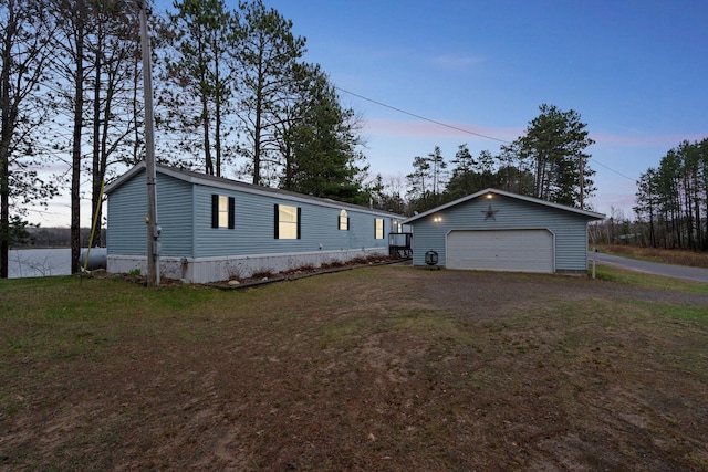 manufactured / mobile home with a garage, an outbuilding, and a yard