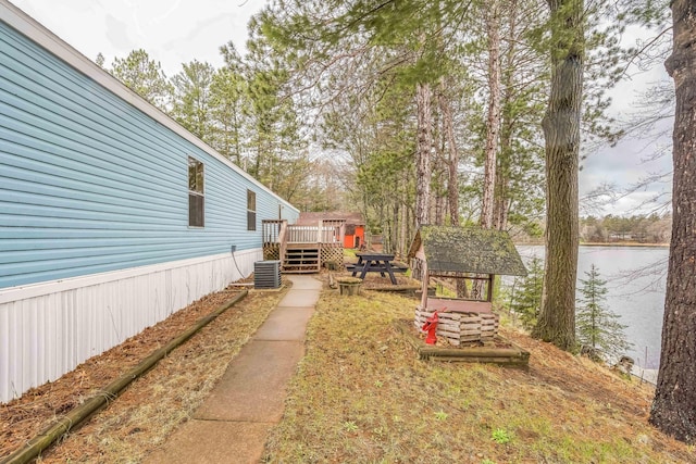 view of yard featuring a deck with water view and cooling unit