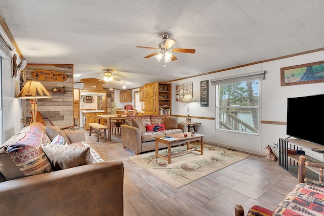 living room with wooden walls, ceiling fan, ornamental molding, and a textured ceiling