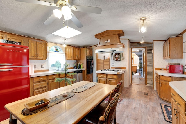 kitchen with a ceiling fan, refrigerator, light countertops, white gas stovetop, and oven