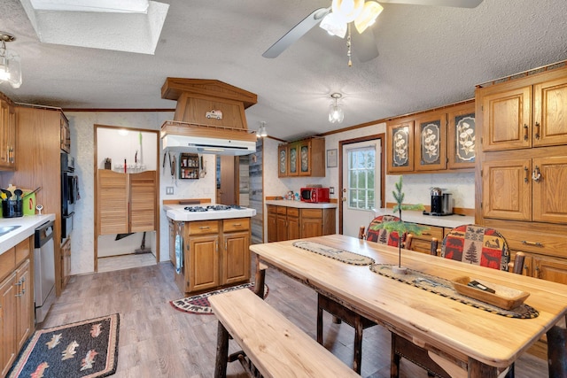kitchen featuring light countertops, ornamental molding, stainless steel dishwasher, and light wood finished floors