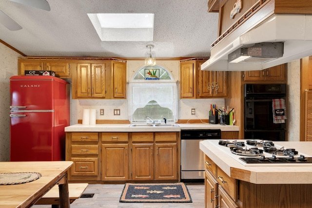 kitchen featuring dishwasher, a sink, freestanding refrigerator, under cabinet range hood, and white gas stovetop