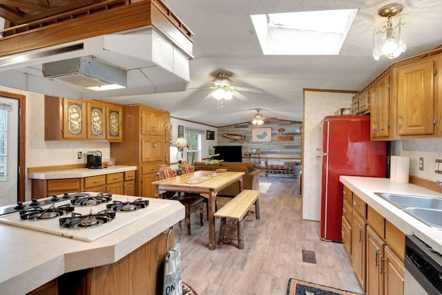 kitchen with white gas cooktop, light wood-style floors, light countertops, under cabinet range hood, and lofted ceiling with skylight