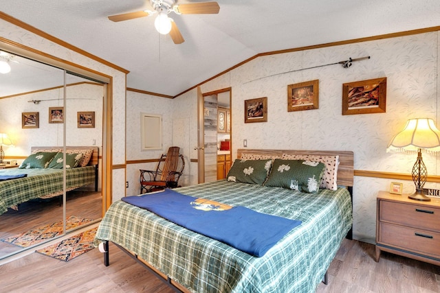 bedroom with ceiling fan, crown molding, vaulted ceiling, wood finished floors, and wallpapered walls