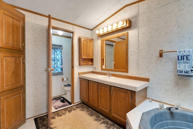 bathroom featuring a jetted tub, a textured ceiling, crown molding, vanity, and toilet