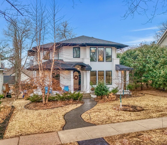 prairie-style home with roof with shingles and stucco siding