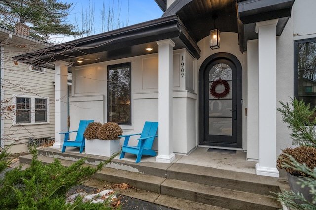 entrance to property with covered porch and stucco siding