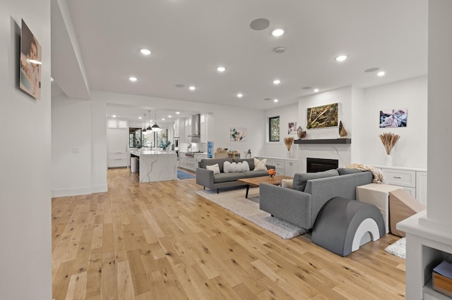 living area with light wood-style flooring, a fireplace, and recessed lighting