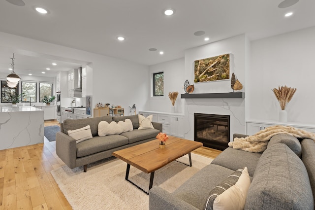 living room with light wood-type flooring, plenty of natural light, recessed lighting, and a high end fireplace