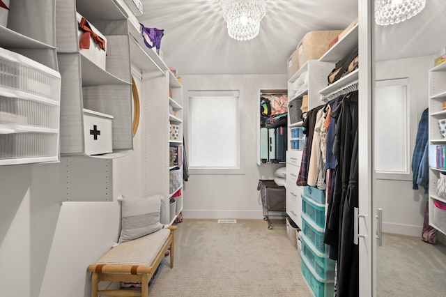 walk in closet featuring light carpet and a notable chandelier