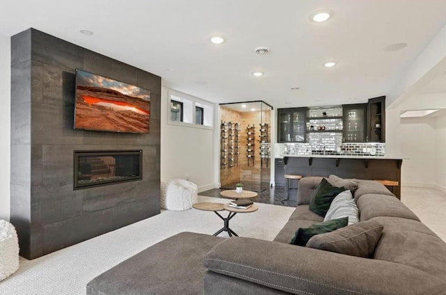 living room featuring wet bar, baseboards, a tiled fireplace, and recessed lighting