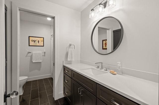 bathroom with toilet, vanity, and baseboards