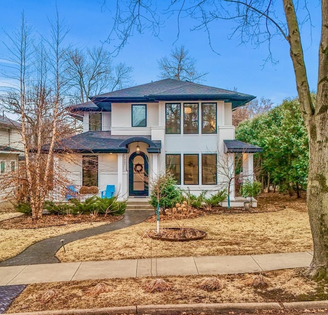 prairie-style home with a shingled roof and stucco siding