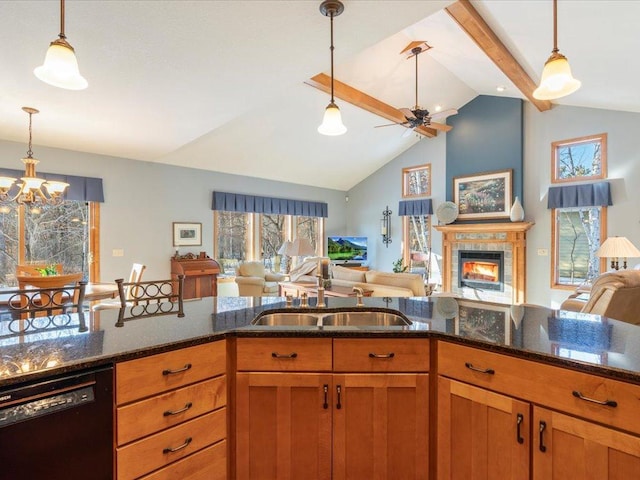 kitchen with sink, dark stone countertops, dishwasher, a tile fireplace, and pendant lighting