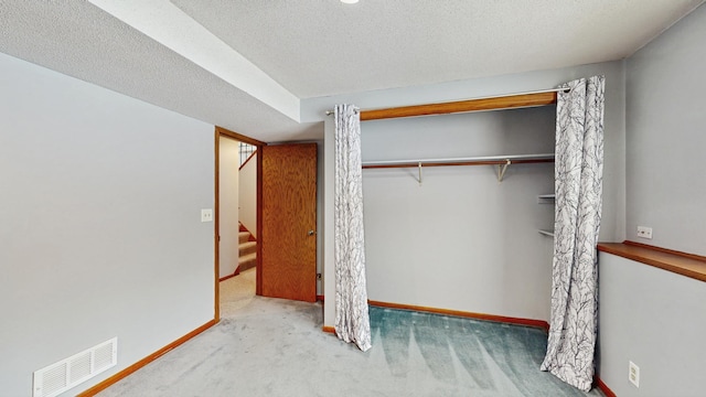 carpeted bedroom with a textured ceiling and a closet