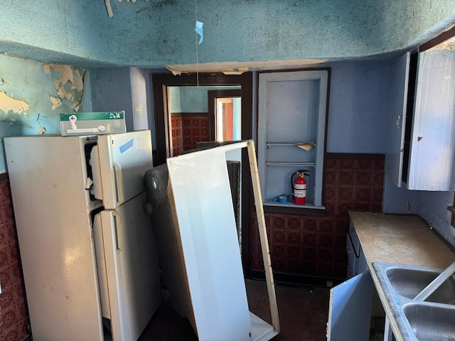 kitchen featuring white refrigerator, sink, and a textured ceiling