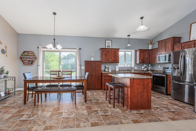 kitchen featuring pendant lighting, a kitchen island, a breakfast bar area, and appliances with stainless steel finishes