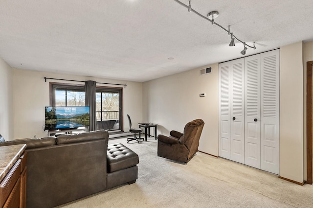 carpeted living room featuring rail lighting and a textured ceiling