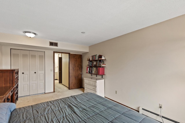 carpeted bedroom featuring baseboard heating, a closet, and a textured ceiling