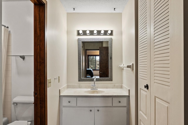 bathroom featuring vanity, toilet, and a textured ceiling