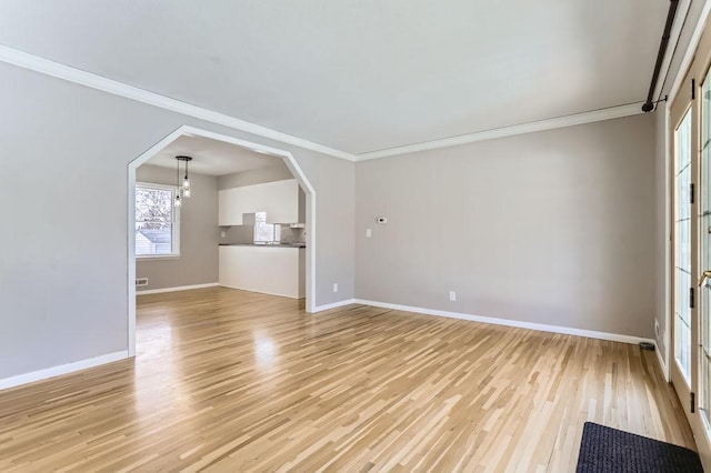 unfurnished living room with arched walkways, light wood-type flooring, and baseboards