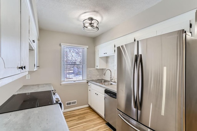 kitchen with light wood finished floors, visible vents, light countertops, appliances with stainless steel finishes, and a sink