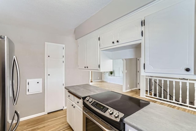 kitchen featuring light wood finished floors, white cabinetry, baseboards, appliances with stainless steel finishes, and a textured ceiling