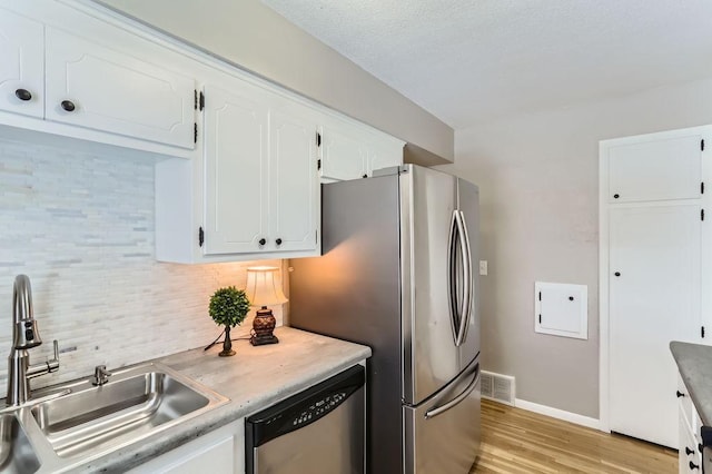 kitchen with visible vents, a sink, stainless steel appliances, white cabinets, and tasteful backsplash