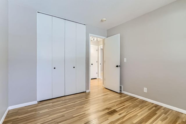 unfurnished bedroom with a closet, baseboards, and light wood-style flooring