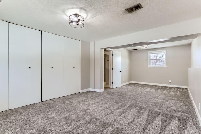 unfurnished bedroom with visible vents, baseboards, carpet flooring, a closet, and a textured ceiling