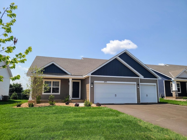 view of front facade with a garage, a front yard, and cooling unit