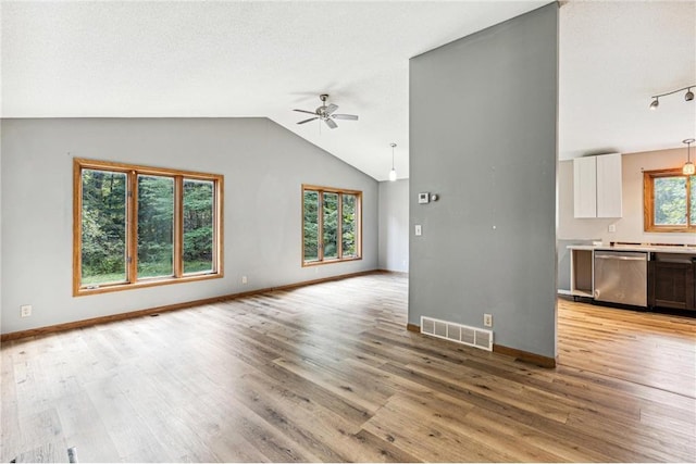 unfurnished living room featuring lofted ceiling, a textured ceiling, ceiling fan, and light wood-type flooring