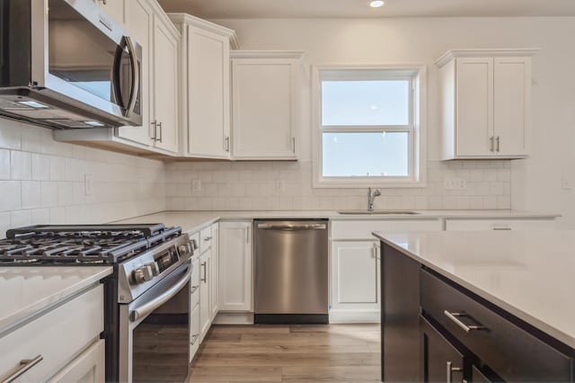 kitchen with white cabinetry, appliances with stainless steel finishes, sink, and decorative backsplash