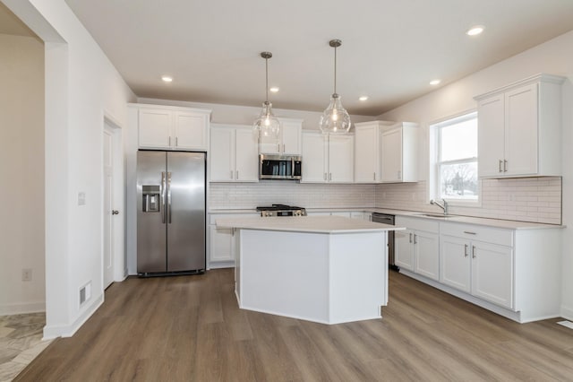 kitchen featuring white cabinetry, pendant lighting, a kitchen island, and appliances with stainless steel finishes