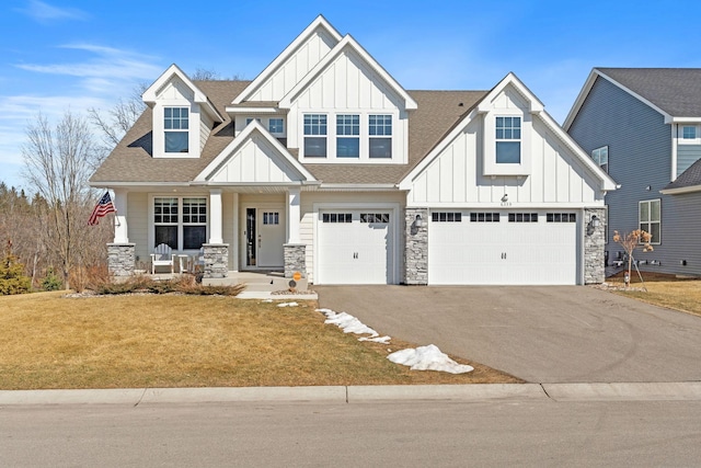 view of front facade featuring board and batten siding, an attached garage, driveway, and roof with shingles