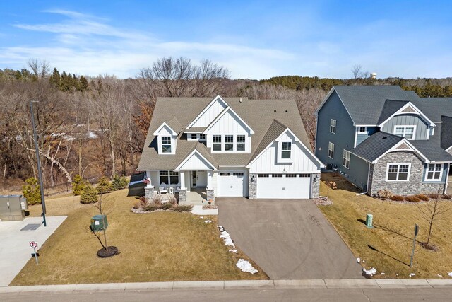 view of front of home featuring driveway, stone siding, a porch, board and batten siding, and a garage