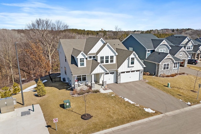 view of front of property featuring driveway, a front lawn, a garage, board and batten siding, and a residential view