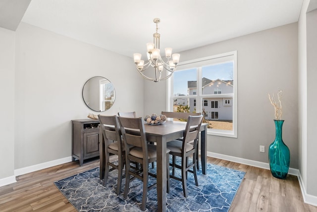 dining area with baseboards, a chandelier, and light wood finished floors