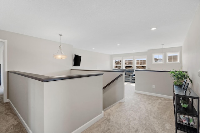 hall with recessed lighting, an upstairs landing, baseboards, and light carpet