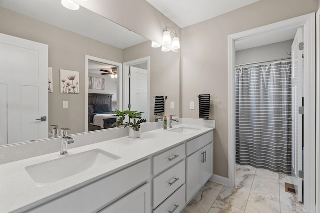 ensuite bathroom with double vanity, a ceiling fan, marble finish floor, and a sink