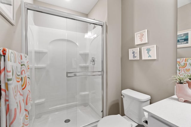 bathroom featuring vanity, toilet, and a shower stall