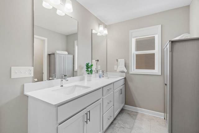 bathroom featuring a sink, baseboards, marble finish floor, and double vanity