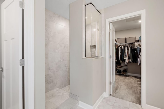 full bathroom featuring a walk in closet, a walk in shower, and baseboards