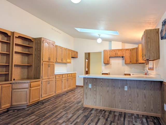 kitchen with dark hardwood / wood-style flooring, sink, kitchen peninsula, and vaulted ceiling with skylight