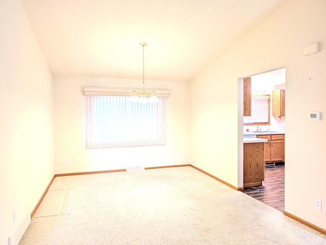 carpeted empty room with sink, a chandelier, and vaulted ceiling